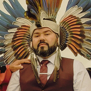 Eric Becerra (center) wears his Aztec dancer headdress, while his parents don the doctoral regalia.