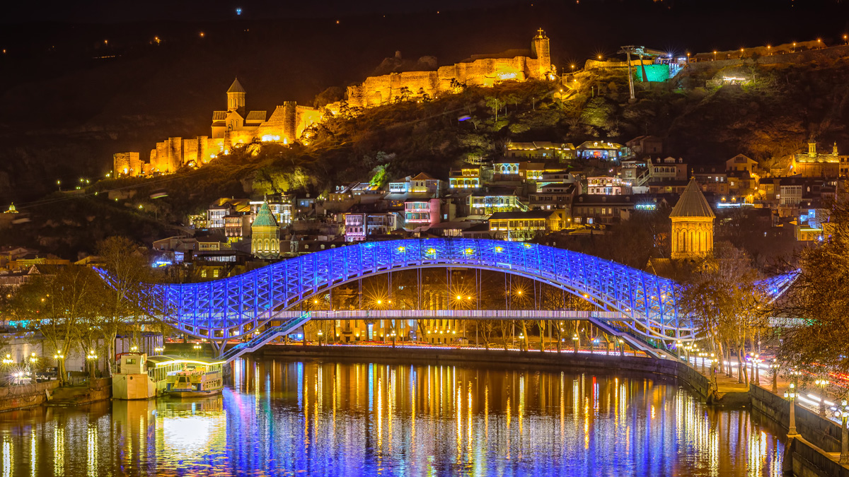 The Bridge of Peace in Tbilisi, Georgia, illuminated at night.