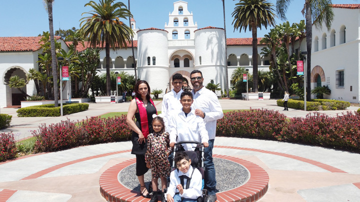 A smiling family stands in front of Hepner Hall at SDSU.