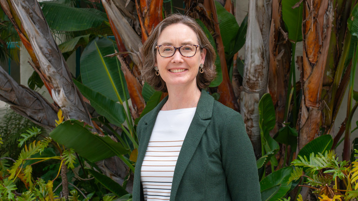 A smiling Jenn Karnopp on campus poses in a green blazer.