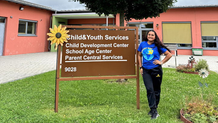 A student stands in front of a Child & Youth Services Center sign.