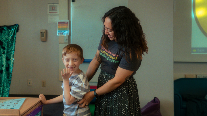 A teacher smiles as she works with a young student.