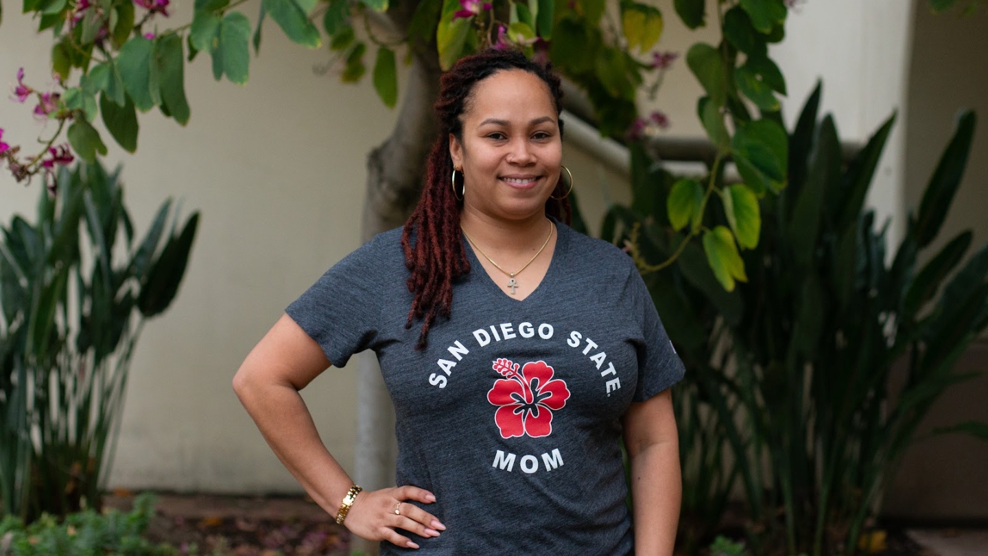 A woman smiles wearing a San Diego State Mom t-shirt.