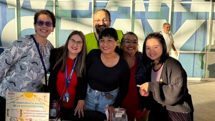 A group of people smile while posing during a resource fair.