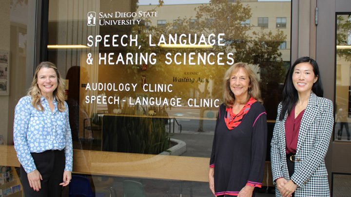 Three women stand in front of a sign reading "SPEECH, LANGUAGE & HEARING SCIENCES"