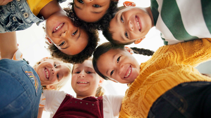 children huddling in a circle and smiling