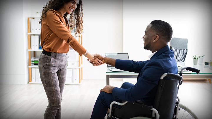 two professionals giving a handshake, one in a wheelchair
